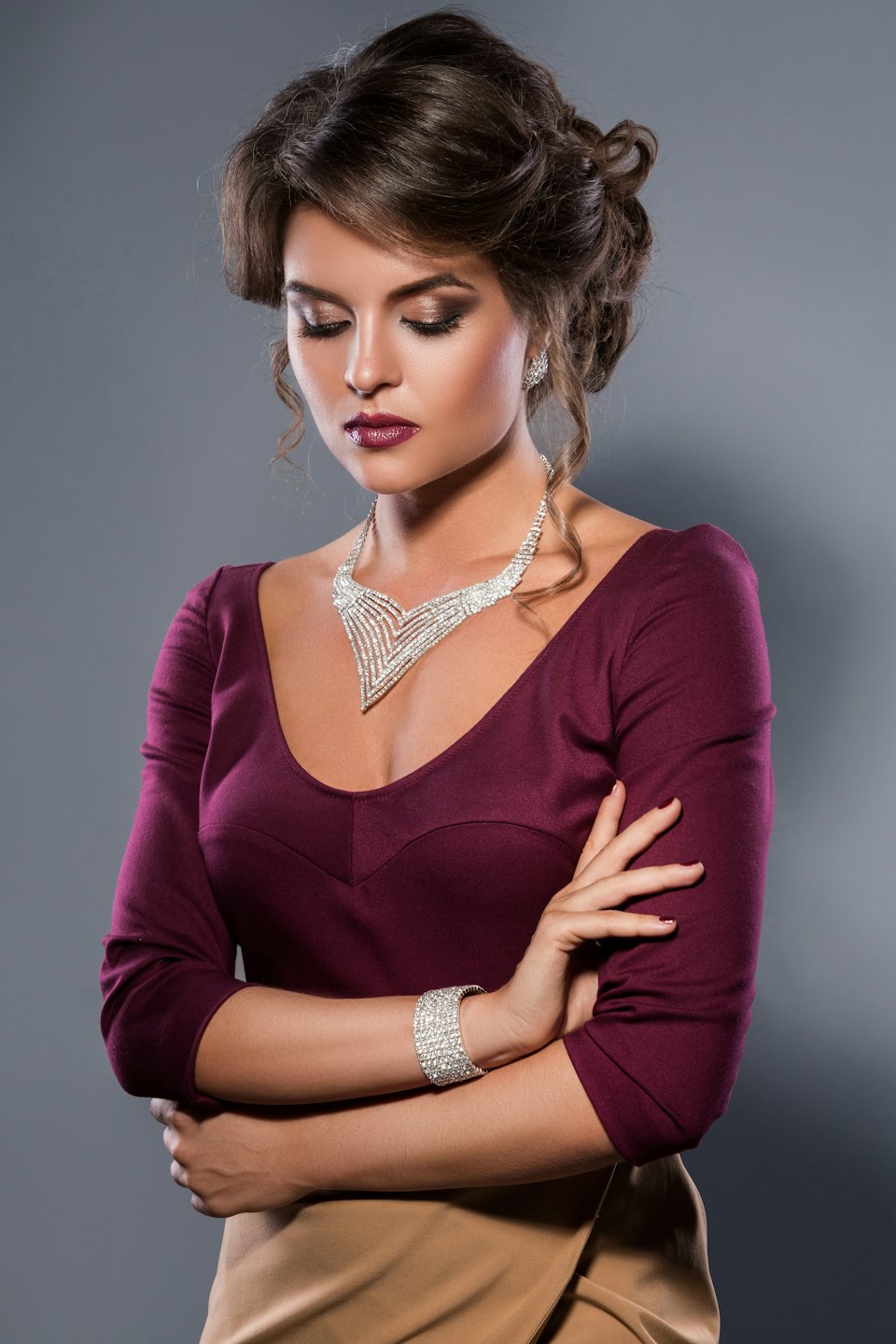 Woman in elegant attire models diamond-like jewelry with eyes closed.