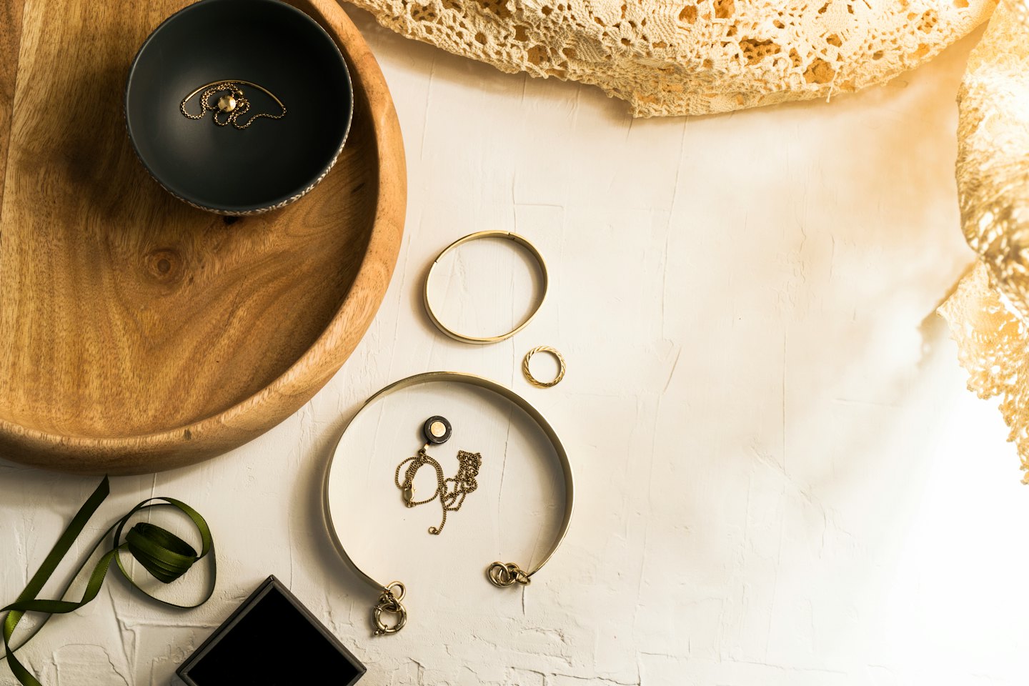 Gold jewelry arranged on a wooden tray and dishes.