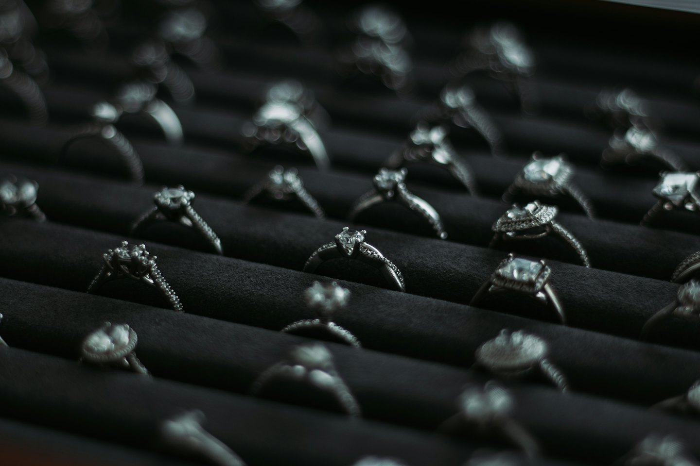 Diamond rings arranged in rows on a black velvet tray.